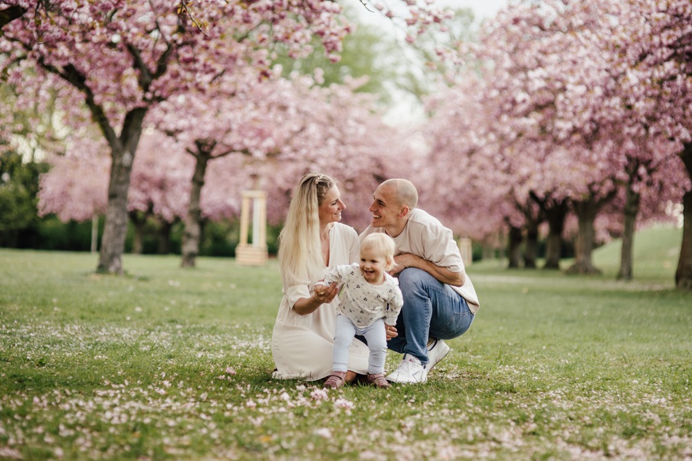 Mutter, Vater und Tochter bei einem fröhlichen Familienshooting zur Kirschblütenzeit in Berlin