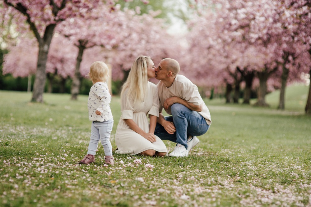 Mutter, Vater und Tochter bei einem fröhlichen Familienshooting zur Kirschblütenzeit in Berlin